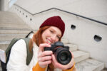 Urban people and lifestyle. Happy redhead woman takes photos, holding professional digital camera, photographing on streets